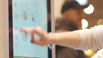 Moscow, Russia - March 16, 2019: Self service ordering machines inside McDonald`s. A woman buys hamburger using kiosk