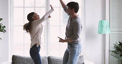 Happy joyful carefree young adult couple dancing in living room