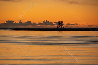 Orange sunset sky over the Baltic sea in Pärnu and silhouette of bird watching tower on horizon