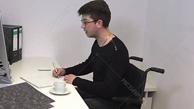 Manager in the office in a wheelchair, a brunette man holds an online conference at the workplace near the computer
