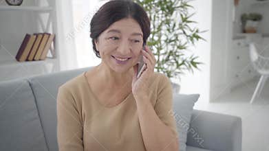 Portrait of beautiful senior Caucasian woman talking on the phone. Pleasant mature brunette lady with brown eyes