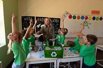 Female school teacher with a group of schoolchildren wearing green t shirts with a white recycling l