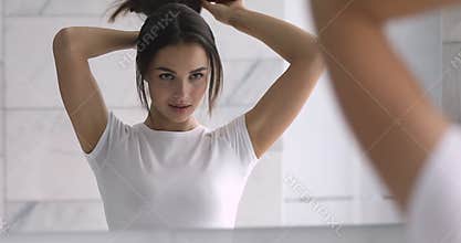 Attractive millennial lady combing long healthy straight hair.