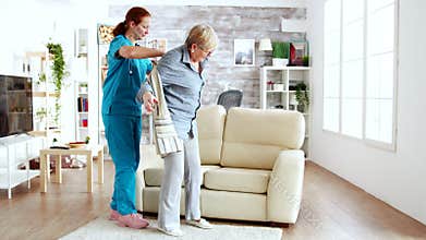 Female nurse helping senior woman getting dressed