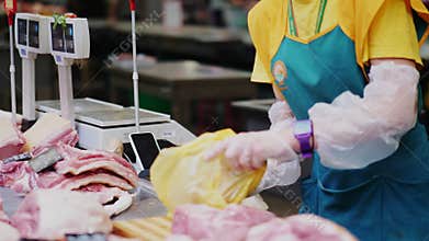 Seller in green apron puts fresh meat into bag at counter