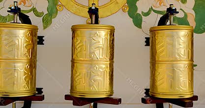 Bhuddhist prayer wheel golden inscribed with a sanskrit prayer and creamy bokeh .