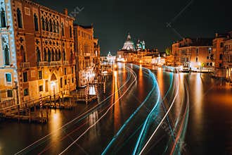 Venice twilight blue night scenery. Light illuminated trails of ferries and boats reflected on the Grand Canal surface