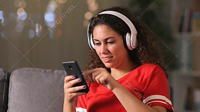 Arab girl listening to music checking phone at home