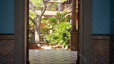 4k video of camera moving thorugh big doorway in patio with garden and fountain inside beautiful old palace in spanish