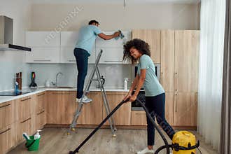 Cleaning experts. Two young professional cleaners in uniform working together in the kitchen. Young caucasian man