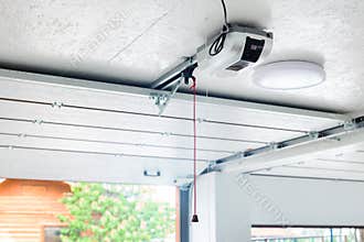 Opening door and automatic garage door opener electric engine gear mounted on ceiling with emergency cord. Double place empty