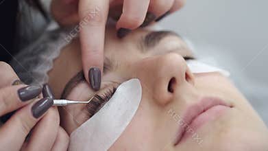 The lash technician is curling the eye lashes up with a tool