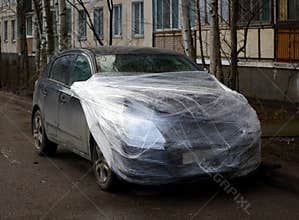 Wrecked car wrapped in plastic wrap in the yard of a house