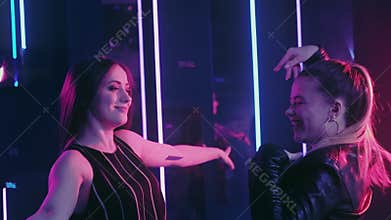 Neon girls amused female friends dancing nightclub