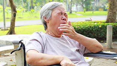 Asian senior woman has sleepy expression,female elderly yawning covering open mouth with hand,old people feel yawn,doze,sleepy in