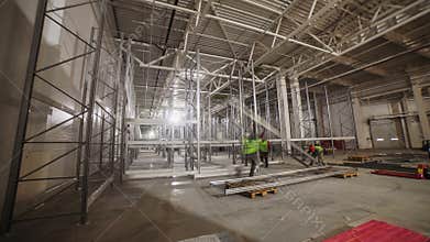 Workers assemble high racks with metal beams in warehouse