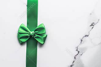 Green silk ribbon and bow on marble background, St Patricks day present or Christmas glamour gift decor for luxury digital brand,