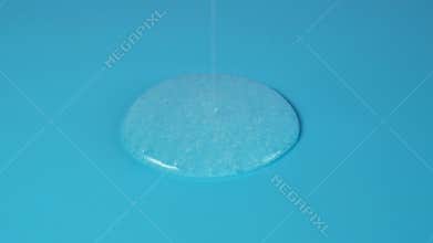 Liquid from xanthan gum spreads in puddle on blue surface. Natural thickener of xanthan gum