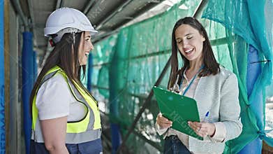 Two women architect and worker shake hands working at street