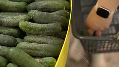 Shopping at the supermarket. Woman in store choosing cucumbers in the vegetable department. Healthy diet.
