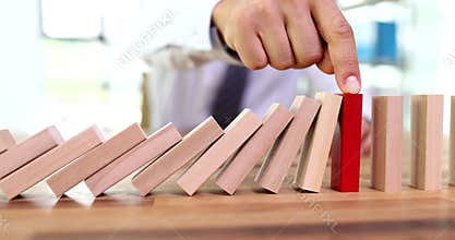 Man with hand stopped red domino and continuously overturned