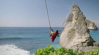 4K video Young woman Playing on the swings at Diamond beach,Bali, indonesia.
