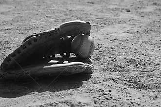 Baseball in glove on field in black and white