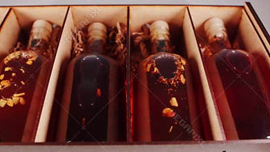 Herbal alcoholic tinctures in a wooden box, close-up. Elite collection alcohol brandy and cognac. Movement from the