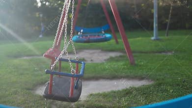Children&#x27;s swings hang empty an idle at a playground on a dull.