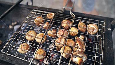Close-up of grilled mushrooms champions in bbq grill net with hot coal underneath. Grilling cooking food outdoors in