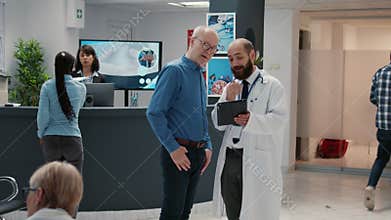 Doctor and senior patient looking at digital tablet in hospital reception