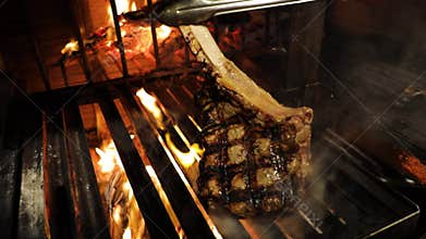 Perfect T-bone steak roasted on a grill, turned on the other side, cooking.