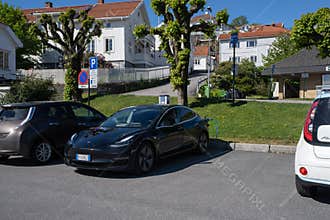 A static shot of a solid black Tesla Model 3 dual motor charging at the Recharge AC charging station