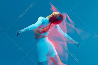 Sporty beautiful girl in white tracksuit dancing on blue background.  fitness model in studio with motion blur