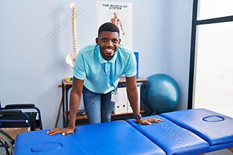 Young african american man physiotherapist smiling confident standing al rehab clinic