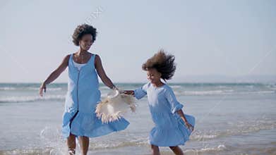 Cute Black girl and her beautiful mum having fun at seashore.