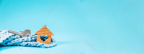 Web banner of mortgage with copy space. Close-up of a key and small keychain wooden house with a heart lying in a