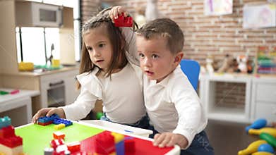 Adorable girl and boy playing with construction block pieces fighting for chair at kindergarten
