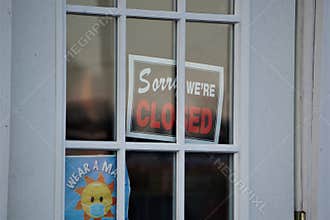 \'Sorry we\'re CLOSED\' sign posted in small business door windows
