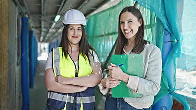 Two women architect and worker holding clipboard working at street