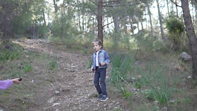 Young children, a boy and a girl walk through a coniferous forest in Turkey in the spring