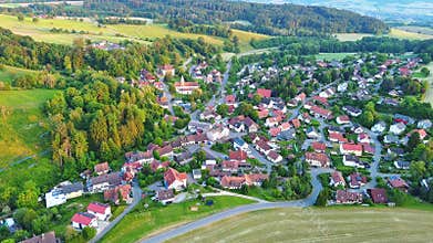 Village with cozy houses, highway passes through it among farmers&#x27; fields, meadows and trees