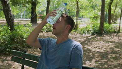 Man suffering from heat wave Cerberus in South Europe. Caucasian male presses bottle of water to face to cool off