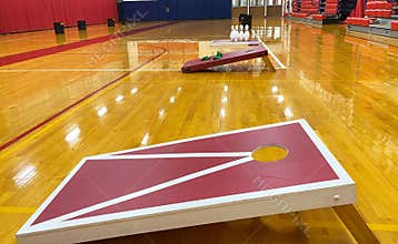Cornhole game boards and bowling set up in a gym