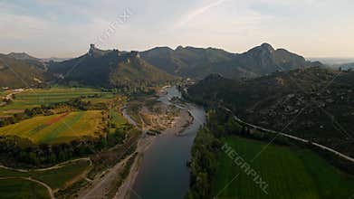 aerial scenic landscape with green fields, meadows, curved mountain river and mountain ridge with high mountains and