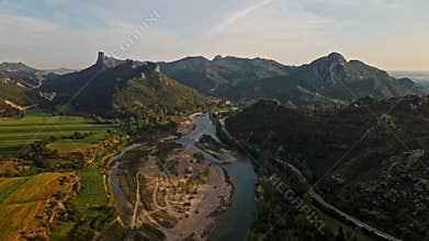aerial scenic landscape with green fields, meadows, curved mountain river and mountain ridge with high mountains and
