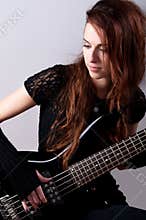 Beautiful girl in black plays bass guitar
