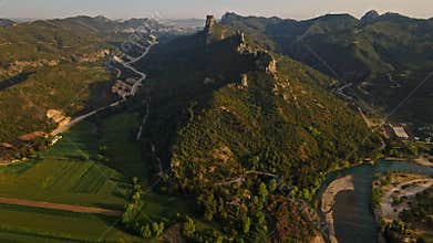 aerial scenic landscape with green fields, meadows, curved mountain river and mountain ridge with high mountains and