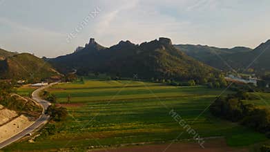 aerial scenic landscape with green fields, meadows, curved mountain river and mountain ridge with high mountains and