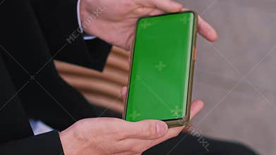 Close up shot of guy using his horizontal smart phone with mock up green screen outdoors, using various gestures while